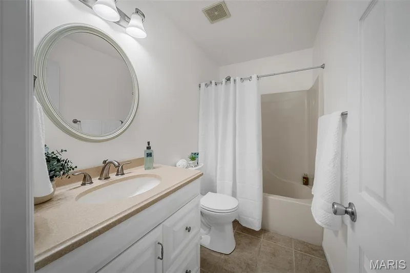 White vanity with a neutral-toned countertop and an oval mirror — 120 Bromley Court, O'Fallon, MO 63368
