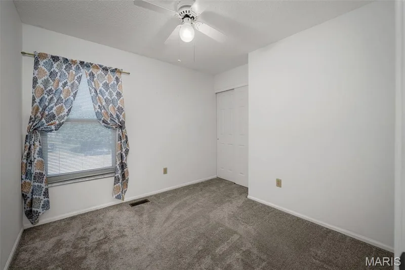 Window with blinds, ceiling fan with integrated lighting, wall-to-wall carpeting, and bi-fold closet doors — 120 Bromley Court, O'Fallon, MO 63368