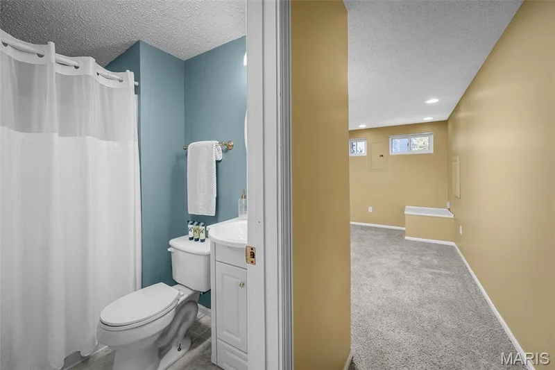 Bathroom featuring a white vanity with integrated sink, toilet, and a shower with a white curtain — 120 Bromley Court, O'Fallon, MO 63368