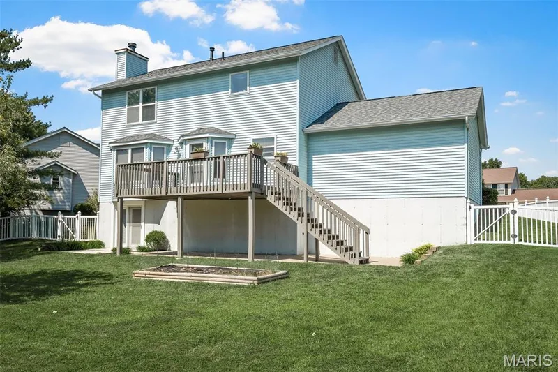 Expansive backyard with a manicured lawn, multi-level deck, and white picket fencing — 120 Bromley Court, O'Fallon, MO 63368