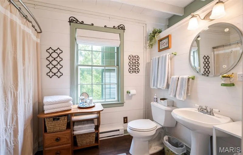 Pedestal sink with chrome fixtures, round wall-mounted mirror, and white shiplap walls — 215 Jackson Street, Augusta, MO 63332