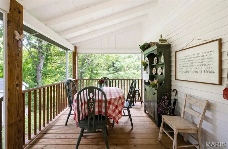 Covered porch with exposed wood flooring, wood support beams, and slatted railings — 215 Jackson Street, Augusta, MO 63332
