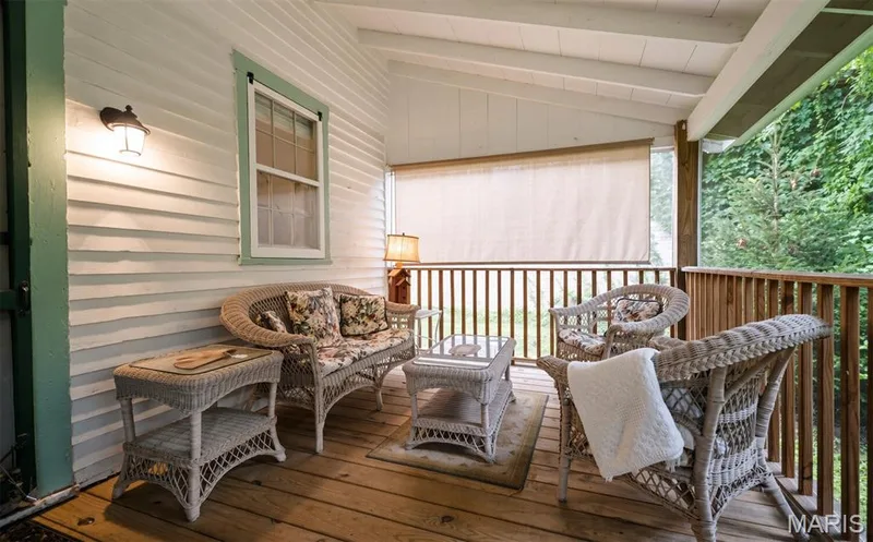 Covered porch with wood-plank flooring, white shiplap siding, and wood railing — 215 Jackson Street, Augusta, MO 63332