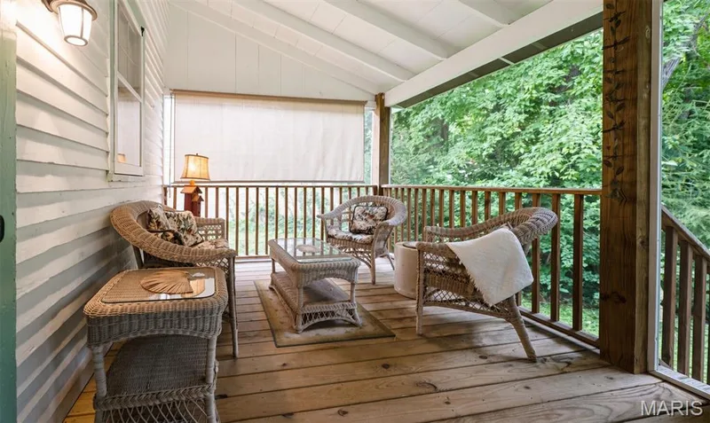 Covered outdoor rear porch with wood plank flooring, screen walls and door in a wooded peaceful setting — 215 Jackson Street, Augusta, MO 63332