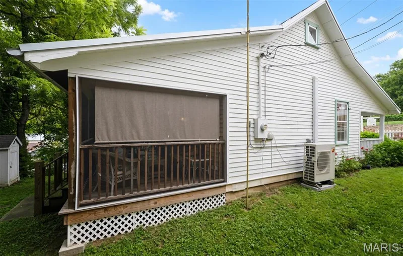 Screened porch with wood railing, white lattice skirting, and horizontal cedar siding on the exterior — 215 Jackson Street, Augusta, MO 63332