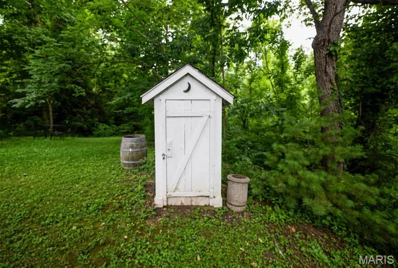 In the backyard ther is a white painted outbuilding with a pitched roof and crescent moon detailing — 215 Jackson Street, Augusta, MO 63332