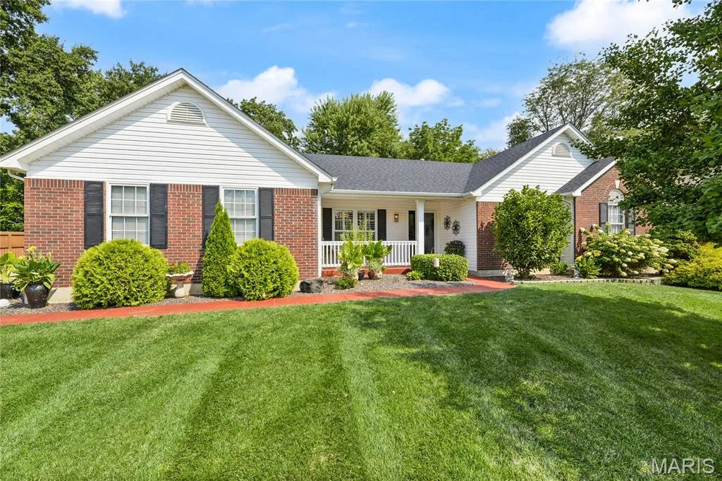 Brick and siding exterior with a covered porch, established lawn, and mature landscaping — 38 Fawn Valley Circle, St Peters, MO 63376