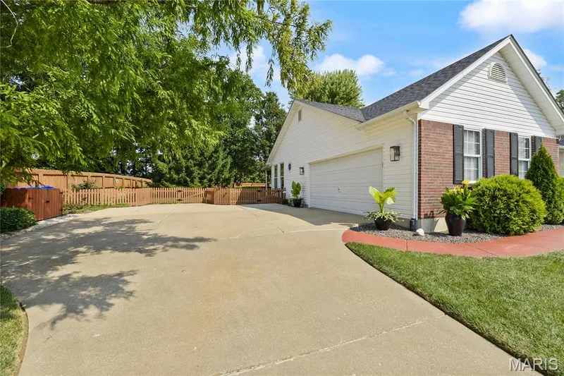 Concrete driveway, attached two-car garage, brick and siding exterior, functional exterior shutters, and a picket fence — 38 Fawn Valley Circle, St Peters, MO 63376