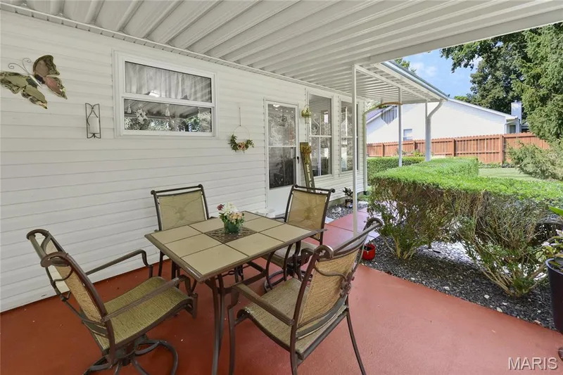 Covered patio with red-toned concrete flooring, white siding exterior, and landscaped perimeter — 38 Fawn Valley Circle, St Peters, MO 63376