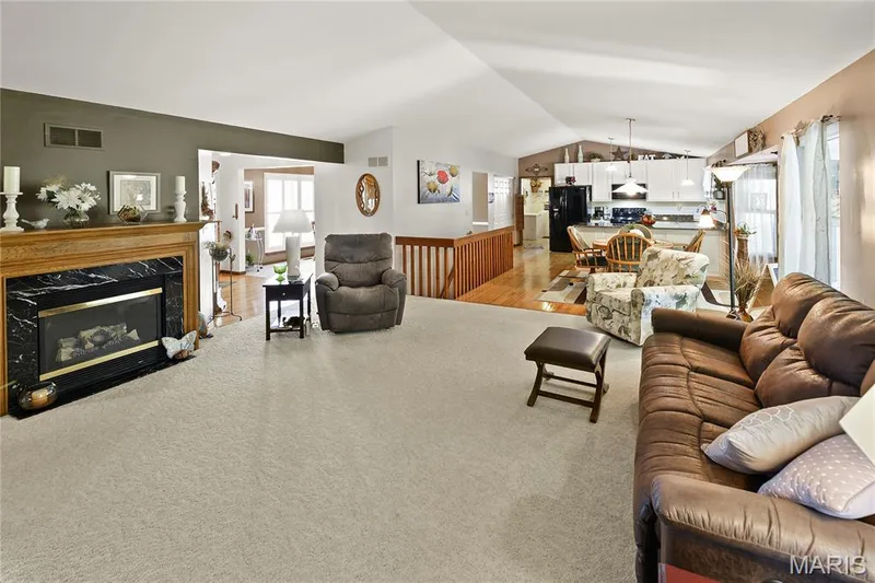 Vaulted ceiling living area with fireplace featuring a wood mantel and black surround — 38 Fawn Valley Circle, St Peters, MO 63376