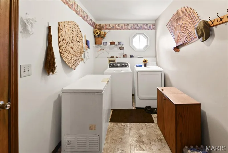 Laundry area featuring a chest freezer, washer, dryer, built-in shelving, and octagonal window — 38 Fawn Valley Circle, St Peters, MO 63376