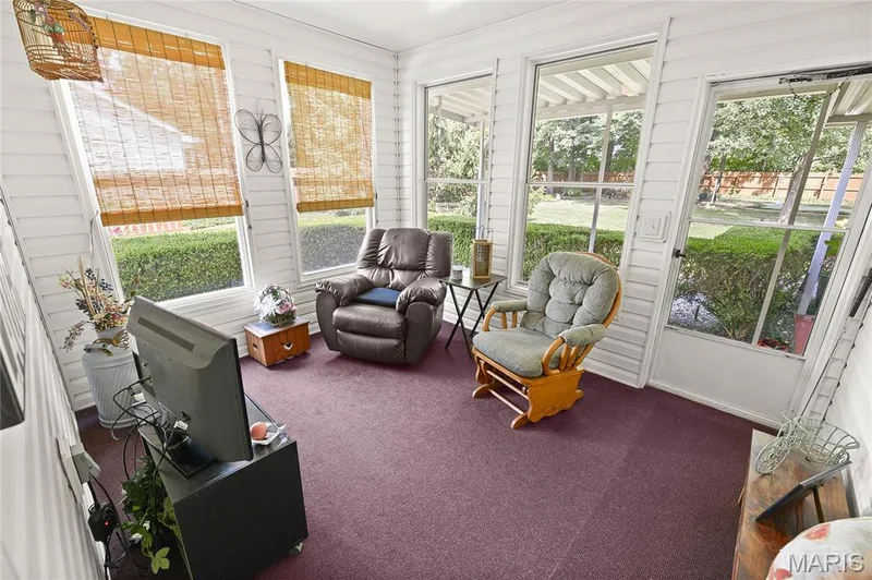 Sunroom featuring multiple windows, slatted wall panels, and a carpeted floor — 38 Fawn Valley Circle, St Peters, MO 63376