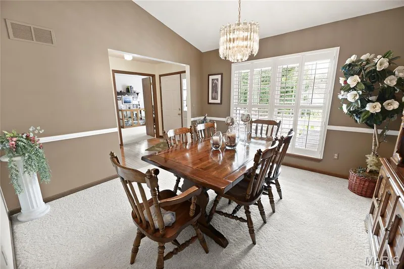 Vaulted ceiling, crystal chandelier, and white plantation shutters, with light-toned carpet and a chair rail accent — 38 Fawn Valley Circle, St Peters, MO 63376