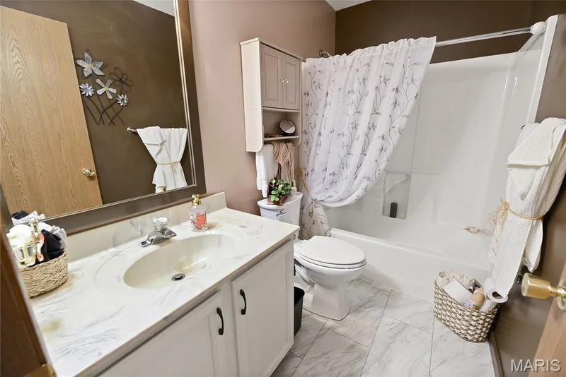 Integrated vanity with a single basin sink, white cabinetry, and a framed wall mirror — 38 Fawn Valley Circle, St Peters, MO 63376