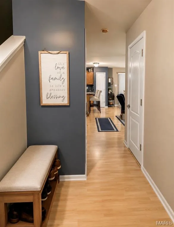 Welcoming entryway with warm wood-finish flooring, soft neutral wall tones, and a slate blue accent wall — 3231 Cog Wheel Station, St Charles, MO 63301