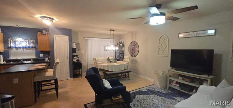 Open-concept living area featuring wood-finish flooring, ceiling fan with integrated lighting, and built-in entertainment cabinetry — 3231 Cog Wheel Station, St Charles, MO 63301