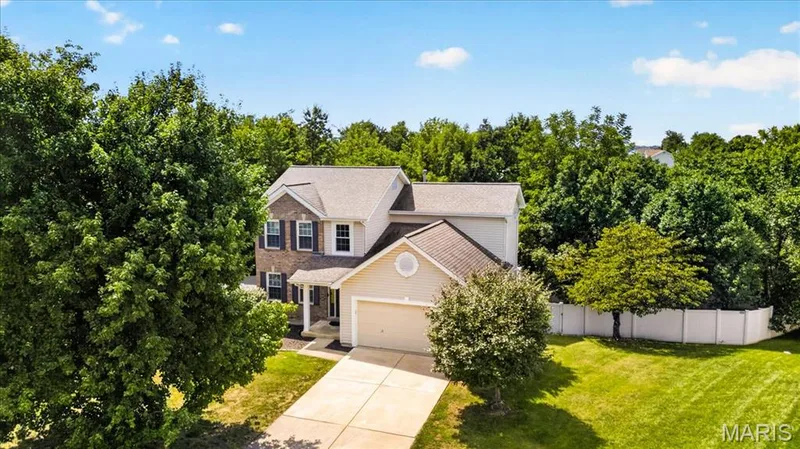 Two-story residence featuring a brick and siding exterior, an attached garage, a driveway, and a white privacy fence — 53 Lions Head Court, O'Fallon, MO 63368