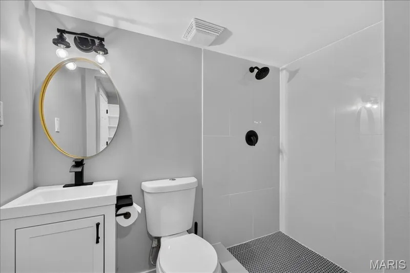 Modern vanity with integrated sink, matte black faucet, and round gold-framed mirror — 53 Lions Head Court, O'Fallon, MO 63368