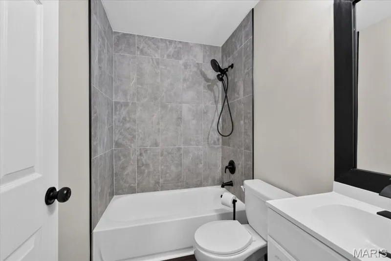 Tub/shower combination featuring grey tile surround and matte black fixtures — 53 Lions Head Court, O'Fallon, MO 63368