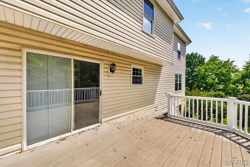 Outdoor deck featuring a sliding glass door, white railing, and exterior wall lantern — 53 Lions Head Court, O'Fallon, MO 63368