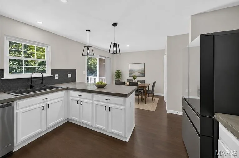 Kitchen featuring white shaker cabinetry, dark countertops, dark tile backsplash, and wood-finish flooring — 53 Lions Head Court, O'Fallon, MO 63368