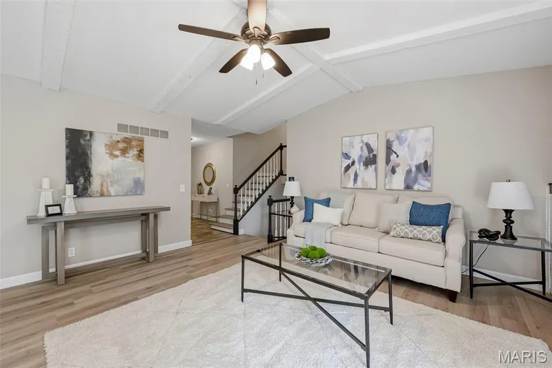 Inviting living room features a vaulted ceiling with beams, ceiling fan with light, wood burning fireplace, professionally painted interior, and LVP flooring. — 3034 Willow Wood Drive, St Charles, MO 63303