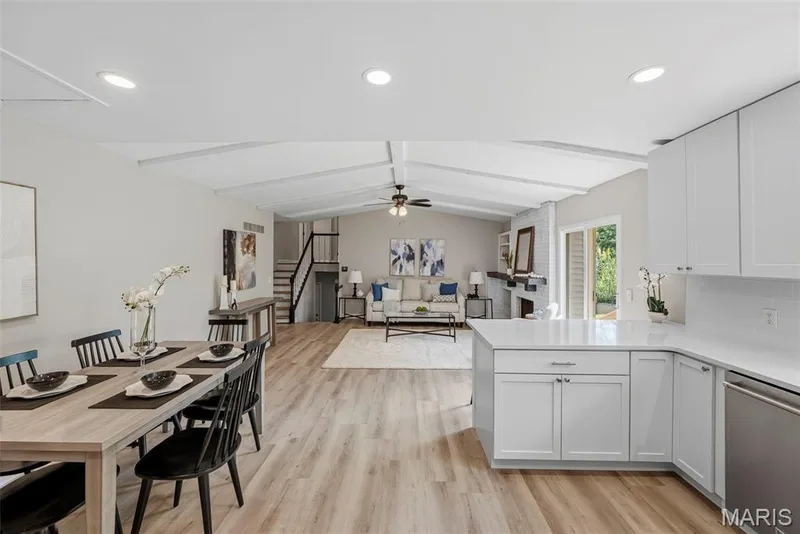 Updated kitchen features 42 inch white cabinetry, granite countertops, breakfast bar, stainless steel appliances, coffee bar, built in pantry, and LVP flooring, with an open layout connecting to the breakfast and living rooms. — 3034 Willow Wood Drive, St Charles, MO 63303
