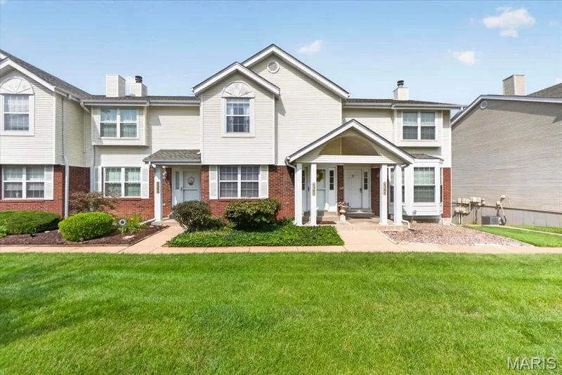 Two-story townhome with brick and siding exterior, arched bay window, covered entry, and manicured landscaping — 1383 Forest Creek Drive #5, St Charles, MO 63303