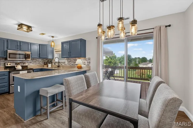 Kitchen with blue cabinetry, stone-finish countertops, and a mosaic tile backsplash — 1383 Forest Creek Drive #5, St Charles, MO 63303