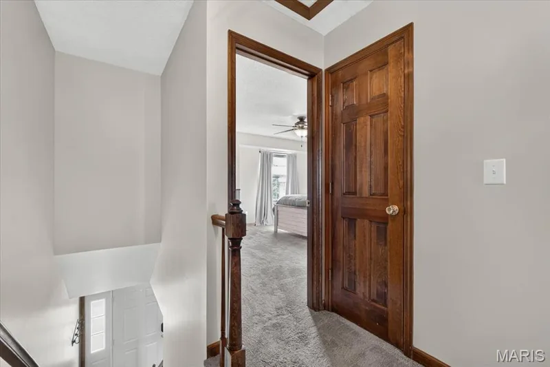 Warm wood-finish door, carpeted flooring, wood-finish railing, painted walls, ceiling fan fixture — 1383 Forest Creek Drive #5, St Charles, MO 63303