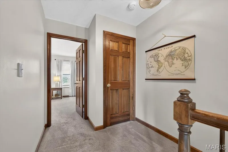 Carpeted hallway with wood-finish doors and trim — 1383 Forest Creek Drive #5, St Charles, MO 63303
