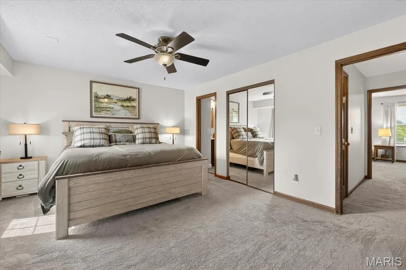 Plush carpeting, ceiling fan with integrated lighting, wood-finish trim, and mirrored closet doors — 1383 Forest Creek Drive #5, St Charles, MO 63303