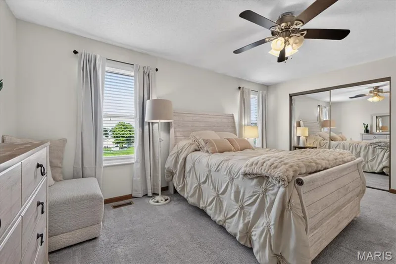 Mirrored sliding closet doors, a ceiling fan with integrated lighting, and a large window with blinds — 1383 Forest Creek Drive #5, St Charles, MO 63303