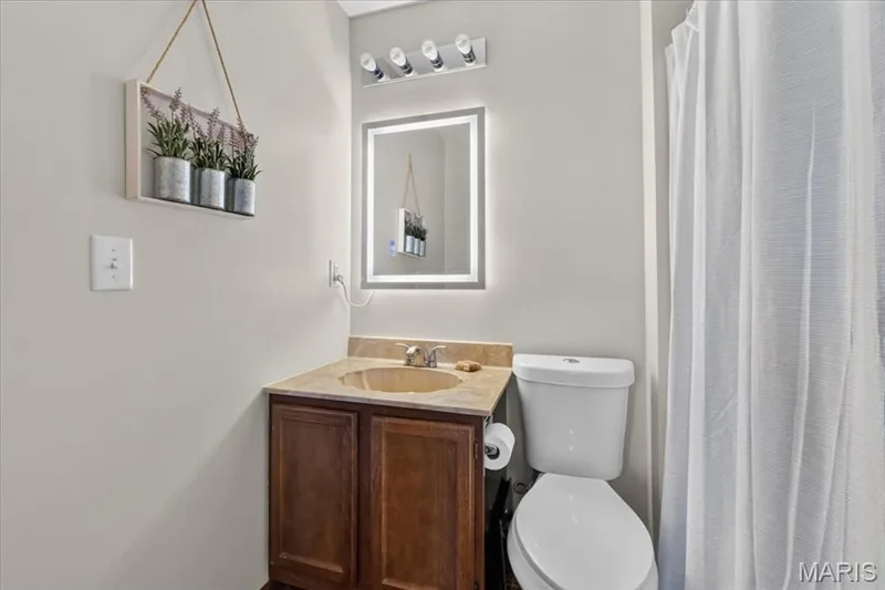 Elegantly appointed half bath featuring a wood-finish vanity with integrated sink, light wood countertop, and chrome fixtures — 1383 Forest Creek Drive #5, St Charles, MO 63303
