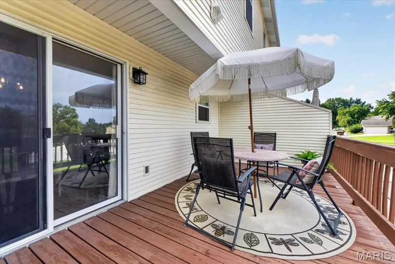 Wood-finish deck with a brown railing, beige siding exterior, and an exterior wall light fixture — 1383 Forest Creek Drive #5, St Charles, MO 63303