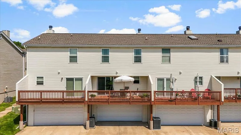 Rear exterior with multiple balconies, white siding, and built-in garage doors — 1383 Forest Creek Drive #5, St Charles, MO 63303
