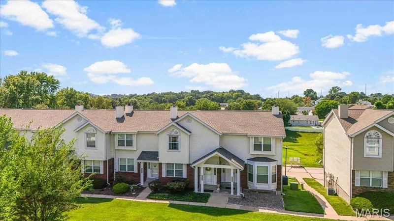 Townhome exterior featuring gabled rooflines, covered entry, bay window, and white siding with brick accents — 1383 Forest Creek Drive #5, St Charles, MO 63303
