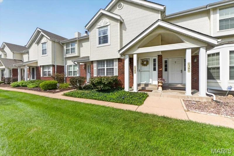 Exterior featuring a brick and siding facade, covered entry with white columns, and a landscaped front yard with green lawn — 1383 Forest Creek Drive #5, St Charles, MO 63303
