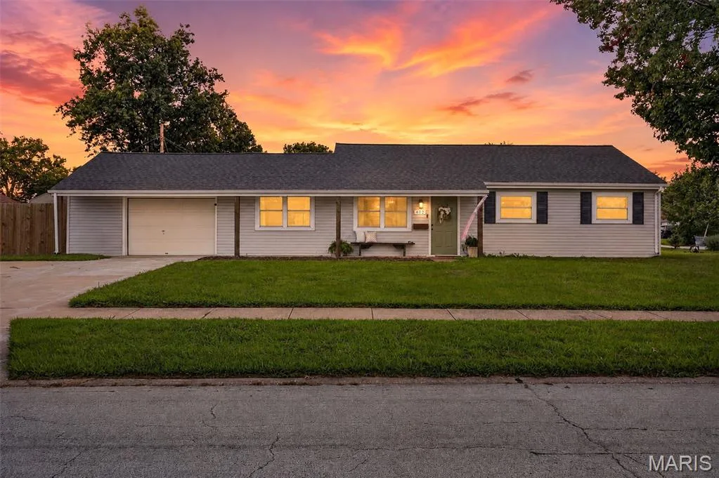 Single-story residence featuring light-colored siding, a dark shingle roof, a front-facing garage, and a concrete driveway — 402 Saint Joseph Avenue, St Charles, MO 63366