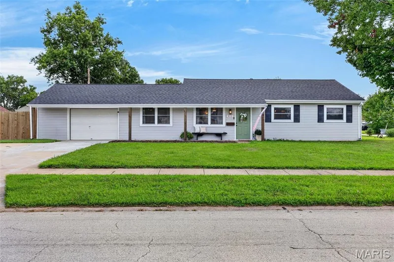 Ranch-style exterior with light gray siding, dark shingle roof, attached garage, concrete driveway, and a front lawn — 402 Saint Joseph Avenue, St Charles, MO 63366
