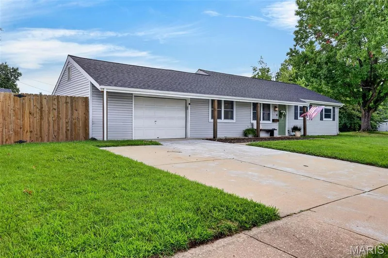 Single-story residence featuring light gray siding, a dark shingle roof, an attached garage, and a concrete driveway — 402 Saint Joseph Avenue, St Charles, MO 63366