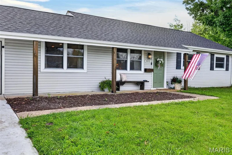 Exterior featuring light-colored siding, dark shingle roof, and a covered porch with wood support posts — 402 Saint Joseph Avenue, St Charles, MO 63366