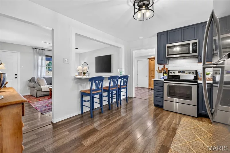 Kitchen with wood-finish flooring, dark blue cabinetry, stainless steel appliances, and a white subway tile backsplash — 402 Saint Joseph Avenue, St Charles, MO 63366