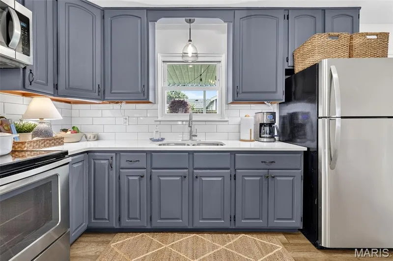 Gray cabinetry with black hardware, white subway tile backsplash, white countertops, stainless steel appliances, and wood-finish flooring — 402 Saint Joseph Avenue, St Charles, MO 63366