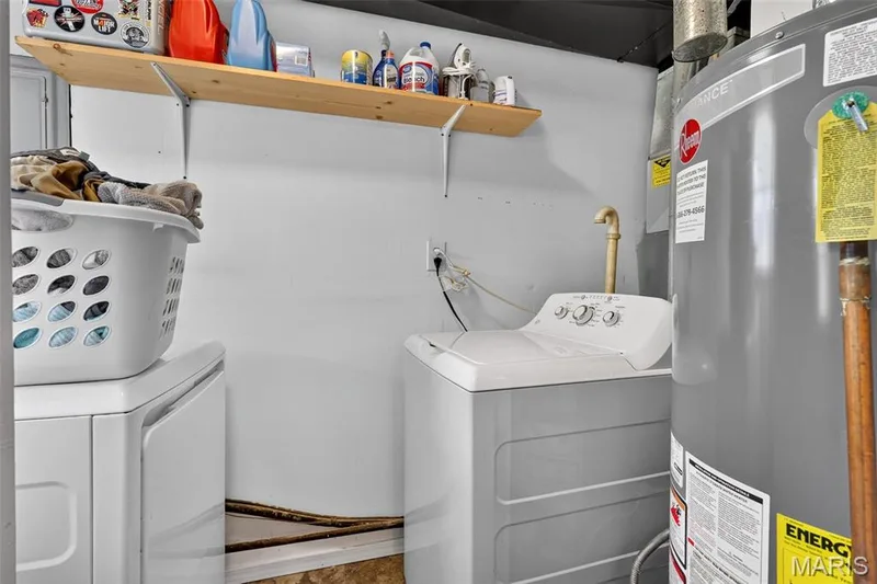 Utility area featuring a top-load washing machine, water heater, and a wall-mounted wooden shelf — 402 Saint Joseph Avenue, St Charles, MO 63366