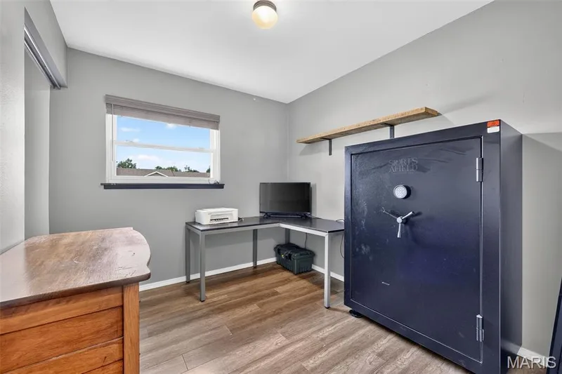 Wood-finish flooring with light gray walls, featuring a window with blinds, and a wall-mounted shelving unit — 402 Saint Joseph Avenue, St Charles, MO 63366