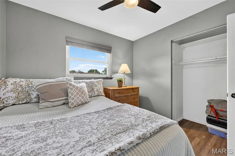 Wall-mounted ceiling fan, window with horizontal blinds, built-in closet with shelving and hanging rod, and wood-finish flooring — 402 Saint Joseph Avenue, St Charles, MO 63366