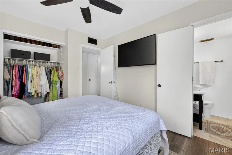 Wood-finish flooring, ceiling fan, built-in closet organization, and an attached bathroom with a pedestal sink — 402 Saint Joseph Avenue, St Charles, MO 63366