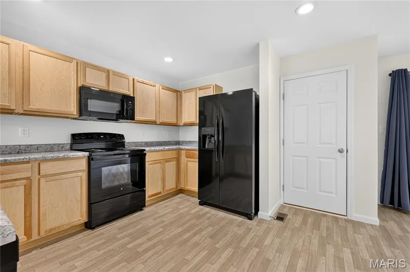 Kitchen featuring light wood-finish cabinetry, black appliances, speckled countertops, and recessed lighting — 352 Fall Harvest Parkway, Wentzville, MO 63385