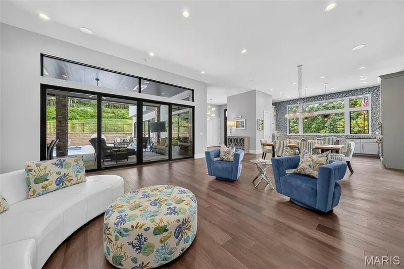 Expansive open-concept living space with wide plank wood-finish flooring, recessed lighting, and a large sliding glass door system — 19256 Saint Albans Forest Lane, Wildwood, MO 63038